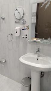 a white bathroom with a sink and a mirror at ﻣﺆﺳﺴﺔ ﺷﻘﻖ ﺍﻟﻘﺎﺭﺍﺕ ﺍﻟﺴﺒﻊ ﺍﻟﻤﺨﺪﻭﻣﺔ in Al Nairyah +13 photos