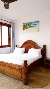 a bedroom with a wooden bed with white sheets and a window at Jamaica House in Nungwi +24 photos