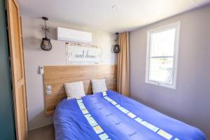 a bedroom with a bed with a blue comforter and a window at Camping Papillon Kinrooi - Vakantiehuis Familie 6P in Kinrooi