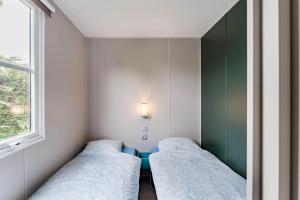 a small room with two beds and a window at Camping Papillon Kinrooi - Vakantiehuis Familie 6P in Kinrooi