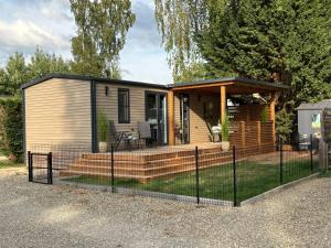 a tiny house with a deck and a gazebo at Camping Papillon Kinrooi - Vakantiehuis Familie 6P in Kinrooi