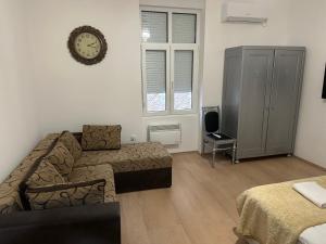 a living room with a couch and a clock on the wall at Natalie's Lodge in Belgrade