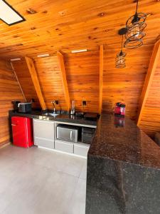 a kitchen with a counter top and wooden walls at Vale dos Ventos - Chalés e Hospedagem in Jaboticatubas