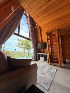 a living room with a couch and a large window at Vale dos Ventos - Chalés e Hospedagem in Jaboticatubas