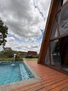 a swimming pool on a deck next to a house at Vale dos Ventos - Chalés e Hospedagem in Jaboticatubas