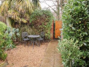 a garden with a table and chairs and a fence at Lilly Cottage in Woodbridge