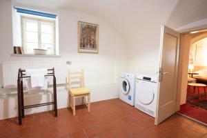 a laundry room with a washing machine and a chair at Ferienwohnung Ottmanach Josefhof in Pischeldorf