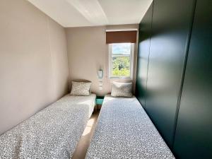 a small room with two beds and a window at Camping Papillon Bouillon - Vakantiehuis Relax 4P in Bouillon