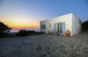 a white building with a sunset in the background at Cycladic Villa with sea view! in Ioulis