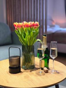 a table with a vase of flowers and two wine glasses at Apartmány Baťovany in Partizánske