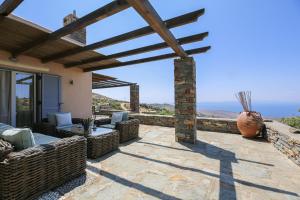 a patio with wicker furniture and a wooden pergola at Cycladic Villa with sea view! in Ioulis