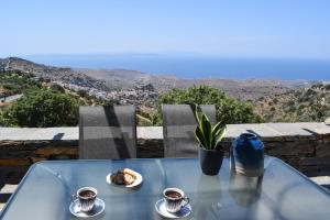 a table with two cups of coffee and food on it at Cycladic Villa with sea view! in Ioulis