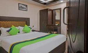 a bedroom with a large bed with green pillows at Starlight Hotels Palm Tree Mylapore Ramakrishna Mutt Road chennai in Chennai