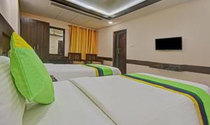 a hotel room with three beds and a flat screen tv at Starlight Hotels Palm Tree Mylapore Ramakrishna Mutt Road chennai in Chennai