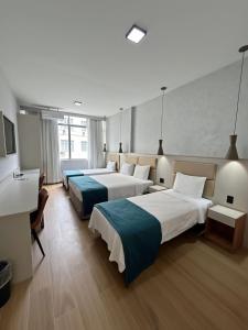 a hotel room with two beds and a desk at Residencial Sausalito in Rio de Janeiro +31 photos