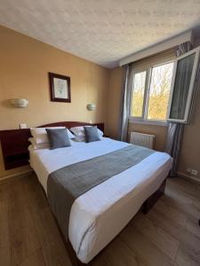 a large bed in a bedroom with a large window at CITY PARC HOTEL - Proche Paris Nord & CDG Aéroport - Parc des Expositions in Aulnay-sous-Bois