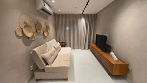 a living room with a couch and a flat screen tv at Ipioca Beach Life Maceió beira mar in Maceió