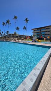 a swimming pool with blue water and palm trees at Ipioca Beach Life Maceió beira mar in Maceió