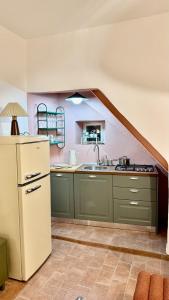a kitchen with green cabinets and a white refrigerator at Pink House - InBorgo in Acquasparta +3 photos