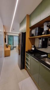 a kitchen with a stainless steel refrigerator and a microwave at Stúdio FRENTE MAR Centro de Convenções Salvador ArtStudio in Salvador