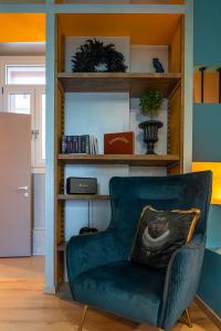 a living room with a green chair and a book shelf at The Urban Parrot Maisonette in Ermoupoli