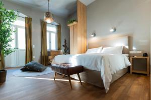 a bedroom with a large white bed and a chair at The Urban Parrot Maisonette in Ermoupoli