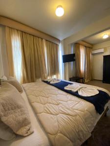 a large white bed in a bedroom with curtains at Hotel Ponta Grossa São Marcos in Ponta Grossa