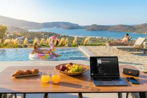 a table with a laptop computer on it next to a pool at Sole Mare Luxury Villa With Sea View & Private Pool in Elounda in Elounda