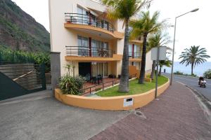 a building with palm trees next to a street at Madalena Sunset by Mill Escapes in Madalena do Mar
