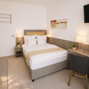 a bedroom with a bed and a desk and a television at Sunny Hotel Regenstauf in Regenstauf