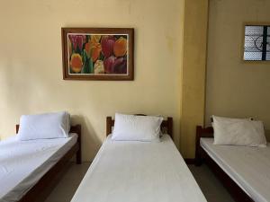 two beds in a room with a painting on the wall at Brussels Garden Inn in Lagawe +3 photos