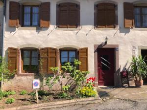 a building with wooden shuttered windows and a red door at Gîte Côté Verre in Meisenthal +8 photos