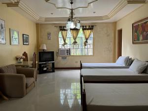 a living room with two beds and a television at Brussels Garden Inn in Lagawe