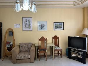a living room with a tv and a table and chairs at Brussels Garden Inn in Lagawe