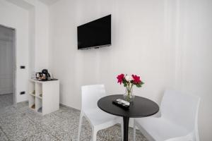 a dining room with a table and a tv on a wall at AuGuStea - Modern Central Suites in Bari