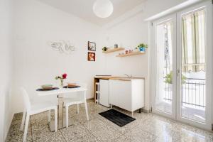 a white dining room with a table and chairs at AuGuStea - Modern Central Suites in Bari