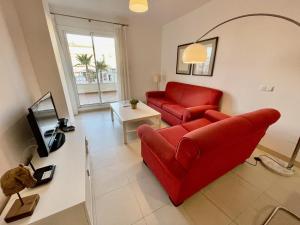 a living room with a red couch and a tv at Plaza España - Central 3 Bedroom apartment - LUAL in Nerja