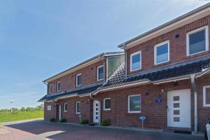 a red brick building with white windows on it at Ferienhaus Domingo in Bensersiel +30 photos