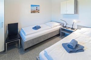 a bedroom with two beds and a chair and a desk at Ferienhaus Bellevue in Bensersiel