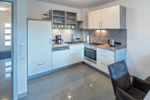 a kitchen with white cabinets and a black chair at Ferienhaus Caskade in Bensersiel
