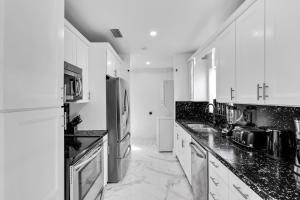 a kitchen with white cabinets and black counter tops at Relax & Fun Hollywood Private Pool | Arcade Game in Hollywood