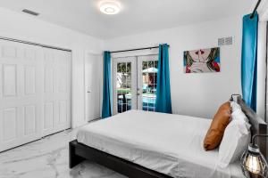 a white bedroom with a bed and blue curtains at Relax & Fun Hollywood Private Pool | Arcade Game in Hollywood