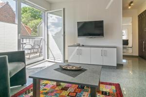 a living room with a tv and a coffee table at Ferienwohnung Bel Air in Bensersiel +8 photos