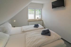 two white beds in a room with a television at Ferienwohnung Bel Air in Bensersiel