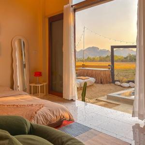 a bedroom with a view of a field from a window at Nana pool villa Kanchanaburi in Ban Hua Hin