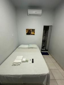 a bed in a white room with avertisementatronatronatronstrationstration at Hotel São Cristóvão in Marabá