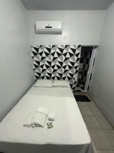 a small bedroom with a white bed with a book on it at Hotel São Cristóvão in Marabá