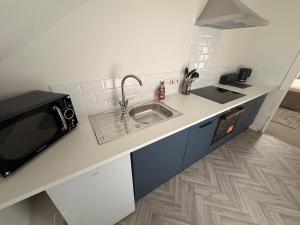 a kitchen with a sink and a microwave at The Loft Ashley Road in Poole +2 photos