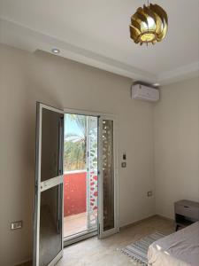 a room with a bed and a glass door with a window at Dar Lina in Tozeur
