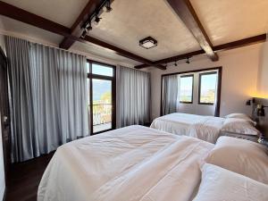 a bedroom with two beds and two windows at Casa Don Cristóbal Hotel y Restaurante Boutique in San Juan La Laguna